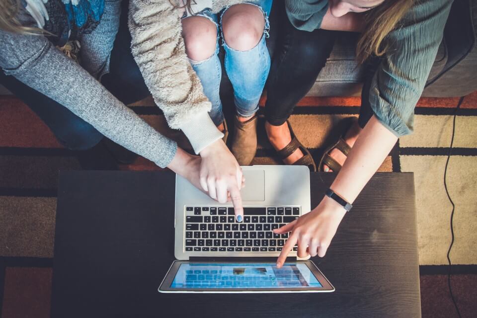 People hovered around computer pointing at website