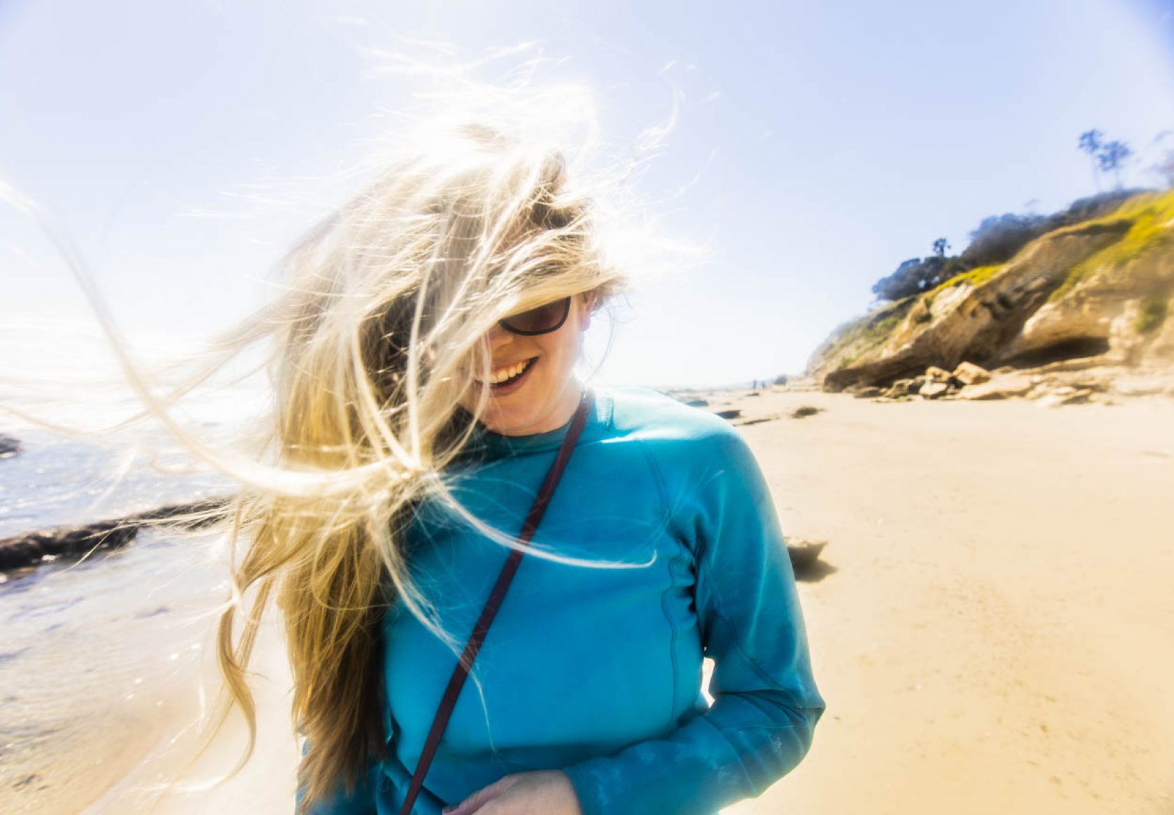 white woman with windswept hair walking on a beach