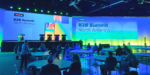 Main stage at Forrester B2B Summit North America with digital displays, colorful lighting and attendees seated at round tables during keynote presentations.