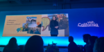 Keynote presentation at Visit California Outlook Forum showing a speaker on stage with themes of Collaboration, Innovation, and Shared Commitment alongside California travel imagery.
